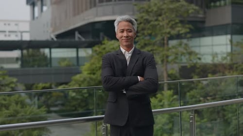 Portrait of Experienced Asian Businessman Crosses Arms Stands on Office Terrace