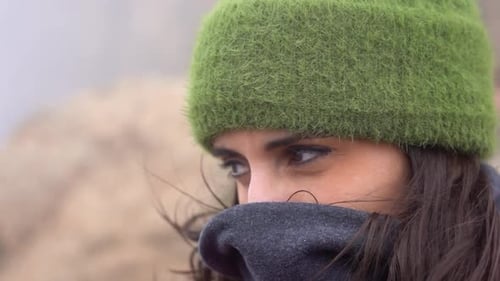Süße Frau, die sich an einem winterkalten Morgen am Berg vor dem Wind schützt. Zeitlupe von