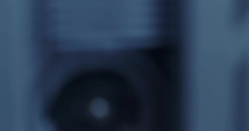 Tilt Up To Extreme Close-Up Of Microcassette Recorder Reel Turning In Cold Blue Lighting