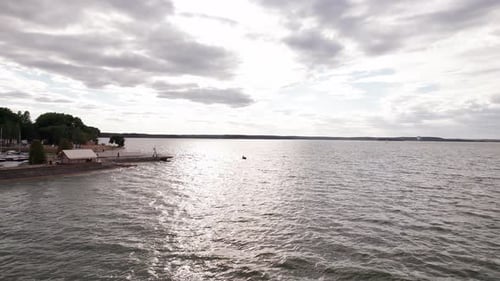 Drone Flies Over Motor Boat Floating on Waves and Panorama of Huge Bay From Landscaped Embankment