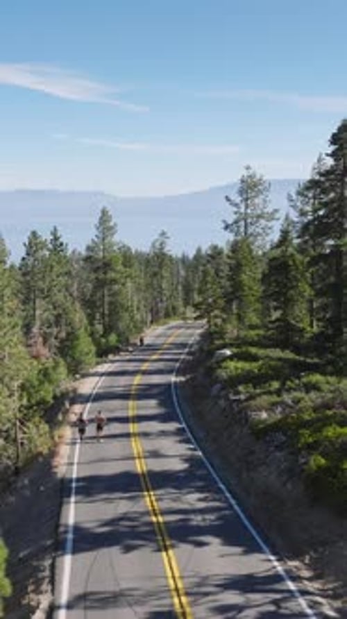 Aerial View of Runners Jogging on a Forest Road with Lush Greenery Mountains and Beautiful Scenery