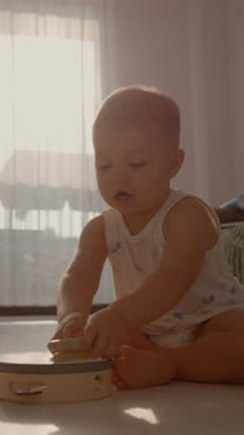 Adorable Infant Playing with Tambourine on Sunny Floor