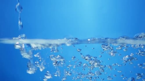 Pure Water Pouring with Bubbles on Blue Background