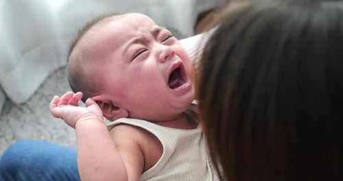 Crying Baby Being Held by Woman Indoors