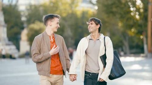 Gay Couple Holding Hands Walking Together in a City Square