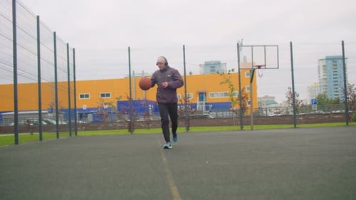 Young Man Dribbling Basketball on Outdoor Court