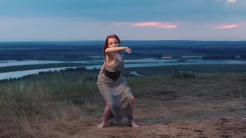 Redhaired Woman Dressed in a Flowing Dress Danced Barefoot on the Green Grass of a Hill