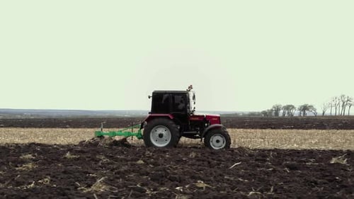Red tractor plowing the field in Ukraine