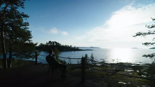 Man Sitting Quietly on Deck Overlooking the Ocean