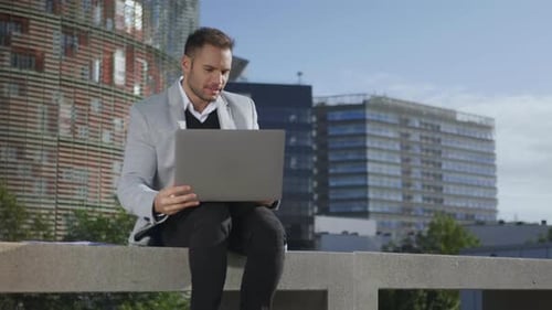 Man Working on Laptop Outdoors in City