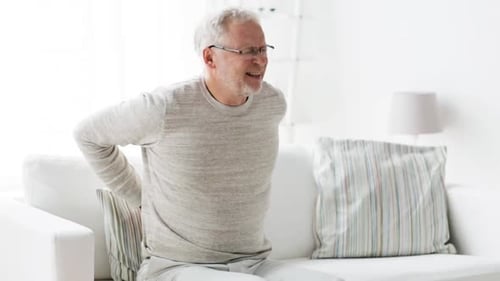 Senior Man Experiencing Back Pain Sitting on Couch