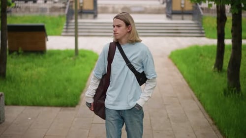 Young Musician Strolling Through Park Casual Performer Walking on Urban Pathway Relaxed Street