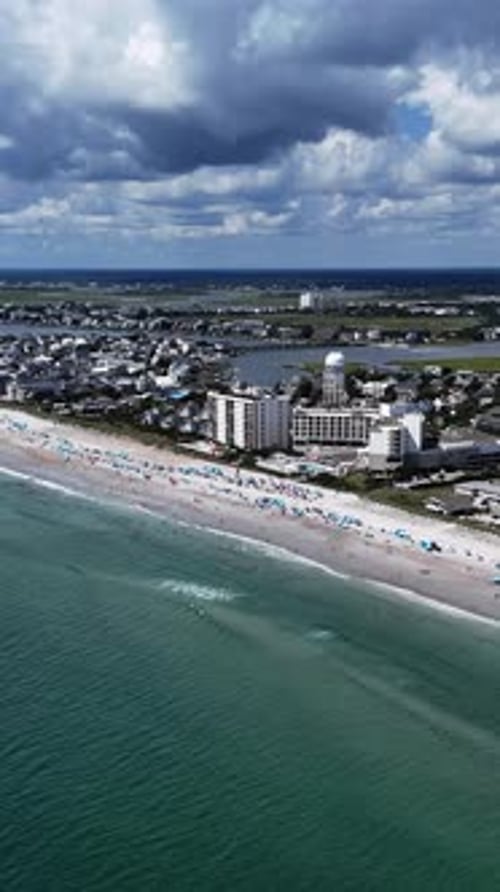 Aerial View of a Beautiful Beach in the USA with Umbrellas Waves and a Lively Coastal Town Under a