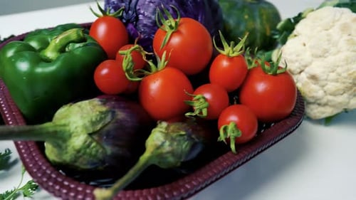 Fresh vegetables including tomatoes, eggplants, green peppers, purple cabbage, and long green beans