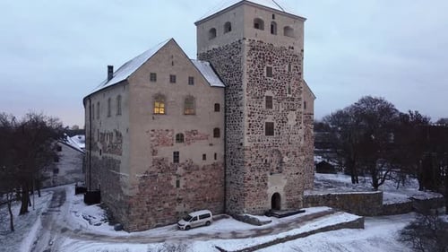 Medieval castle on a cold and snowy afternoon. Ascending drone shot