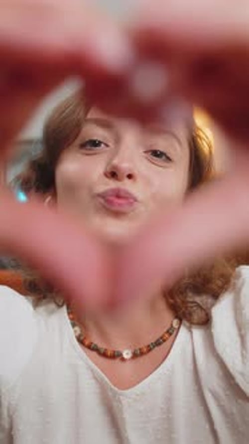 Smiling Woman Makes Heart Shape with Hands