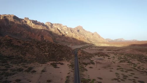 Luftbild einer Autofahrt auf einer Wüstenstraße mit Berghintergrund auf Teneriffa