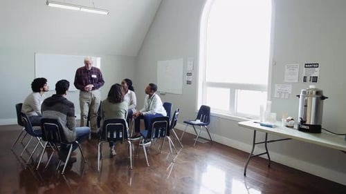 Senior man leads a diverse emotional support group meeting at the community center