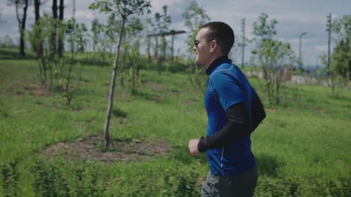 A Young Athletic Man Runs Through a Landscaped and Green Park Sports Lifestyle to Maintain Tone and