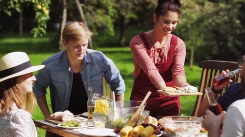 Leisure, Holidays, Eating, People And Food Concept - Happy Friends Having Dinner At Summer Garden...