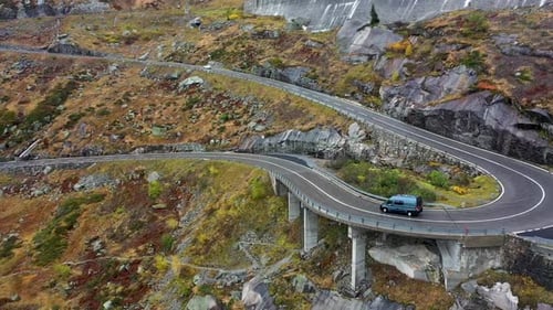 gray camper van driving Grimselpass road in Switzerland in autumn . Aerial view . wet winding road,