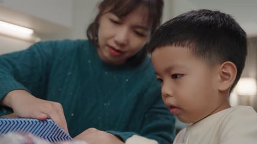 Woman and Young Boy Open a Wrapped Present