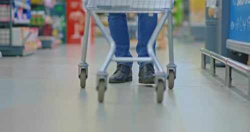 Man with Shopping Cart Walking in Trading Floor Closeup of Feet and Wheels Prores