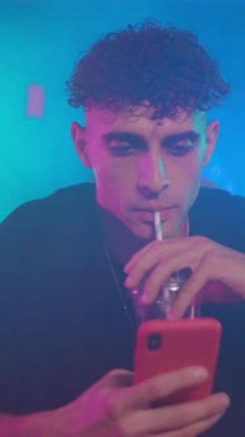 A Young Man Engaged in Using a Smartphone While Surrounded By a Colorful Atmosphere