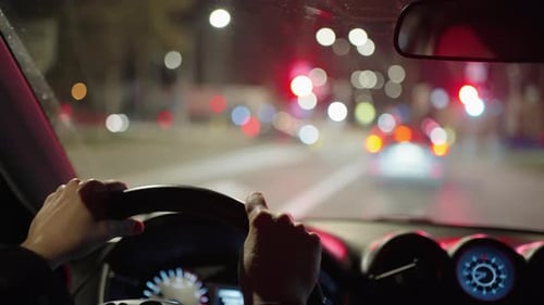 Woman Drives a Car at Night Through the Suburban Area of a Big City