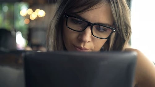 Young woman enjoys tablet computer and coffee at a bright modern cafe