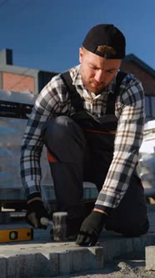 Construction Worker Laying Paving Stones with Hammer