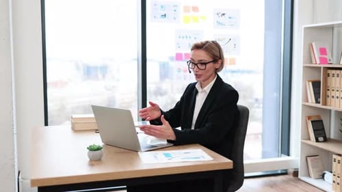 Professional Businesswoman in Headset Multitasking During Video Call in Office