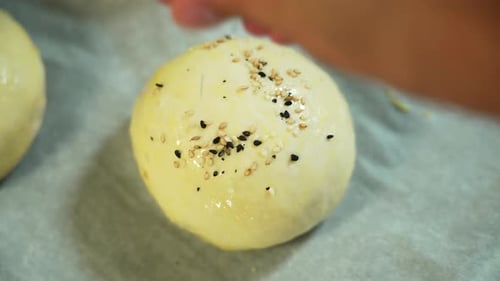 Sprinkling Sesame Seeds on a Ball of Dough