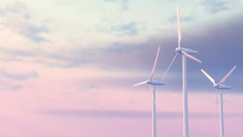 Endless looping video of three wind turbines standing tall and rotating against sky during dusk