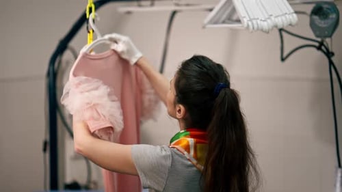 Woman Inspecting Pink Dress with Frilly Sleeves
