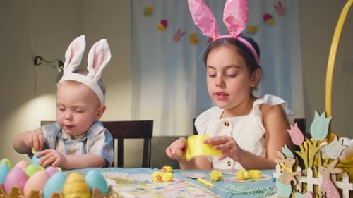 Two Cheerful Children a Girl and a Boy Decorate Easter Eggs