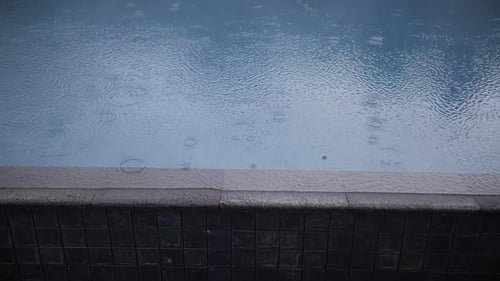 Rain Drops Falling on Water Surface of Blue Swimming Pool