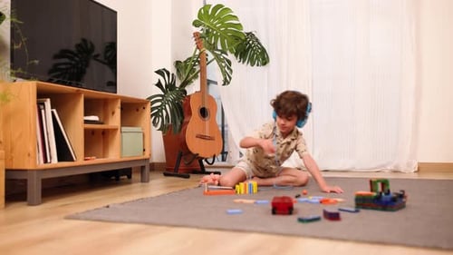 Boy with Headphones Plays with Toy Indoors