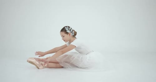 Girl in Tutu Sitting and Stretching in Studio