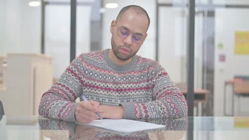 Young Adult Filling Out a Form at Desk