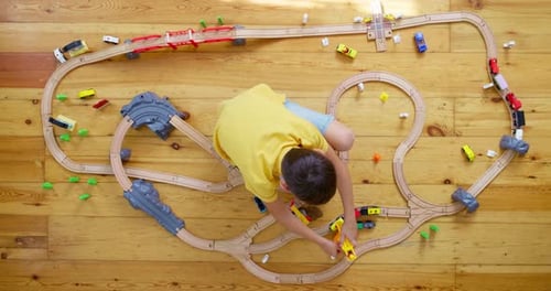 Child Playing with Toy Train Tracks at Home