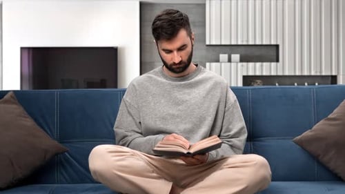 Man Reading Book on Sofa in Living Room