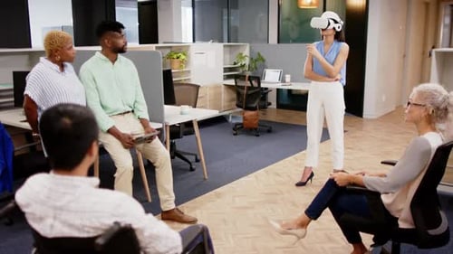 Using VR headset, woman presenting to colleagues in modern office meeting