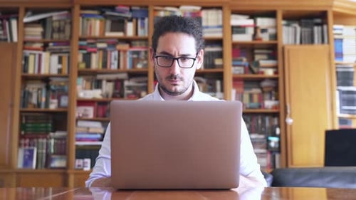 Success in business and education. Young male with glasses working on laptop