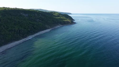 Beach Between a Ledge Covered with Vegetation and a Black Sea Under a Clear Blue Sky
