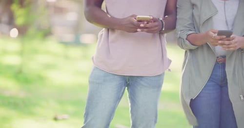 Group of Young Adults Using Phones Together Outside