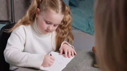 School Girl with Long Blonde Hair in White Sweater Sitting at Table