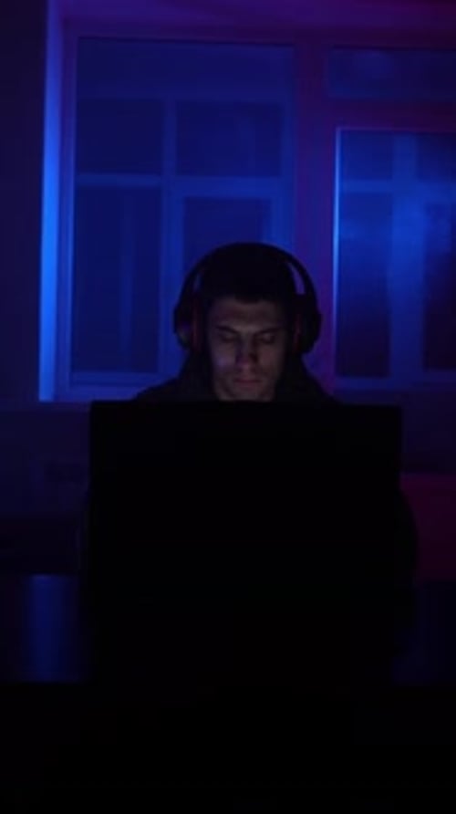 Young Man with Headphones in Neon Lit Room