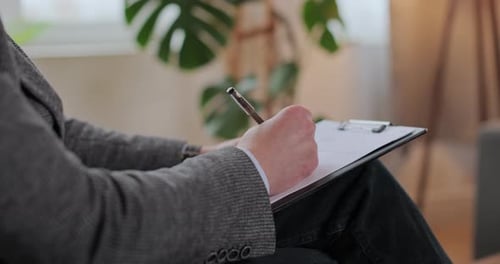 Psychologue en gros plan écrivant des notes d'observation pendant une séance de thérapie avec un patient assis