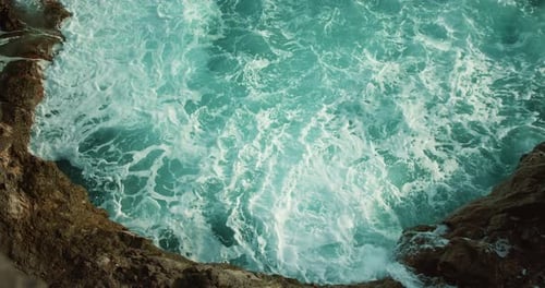 Raging ocean waves close-up water white foam on rocky coastline.